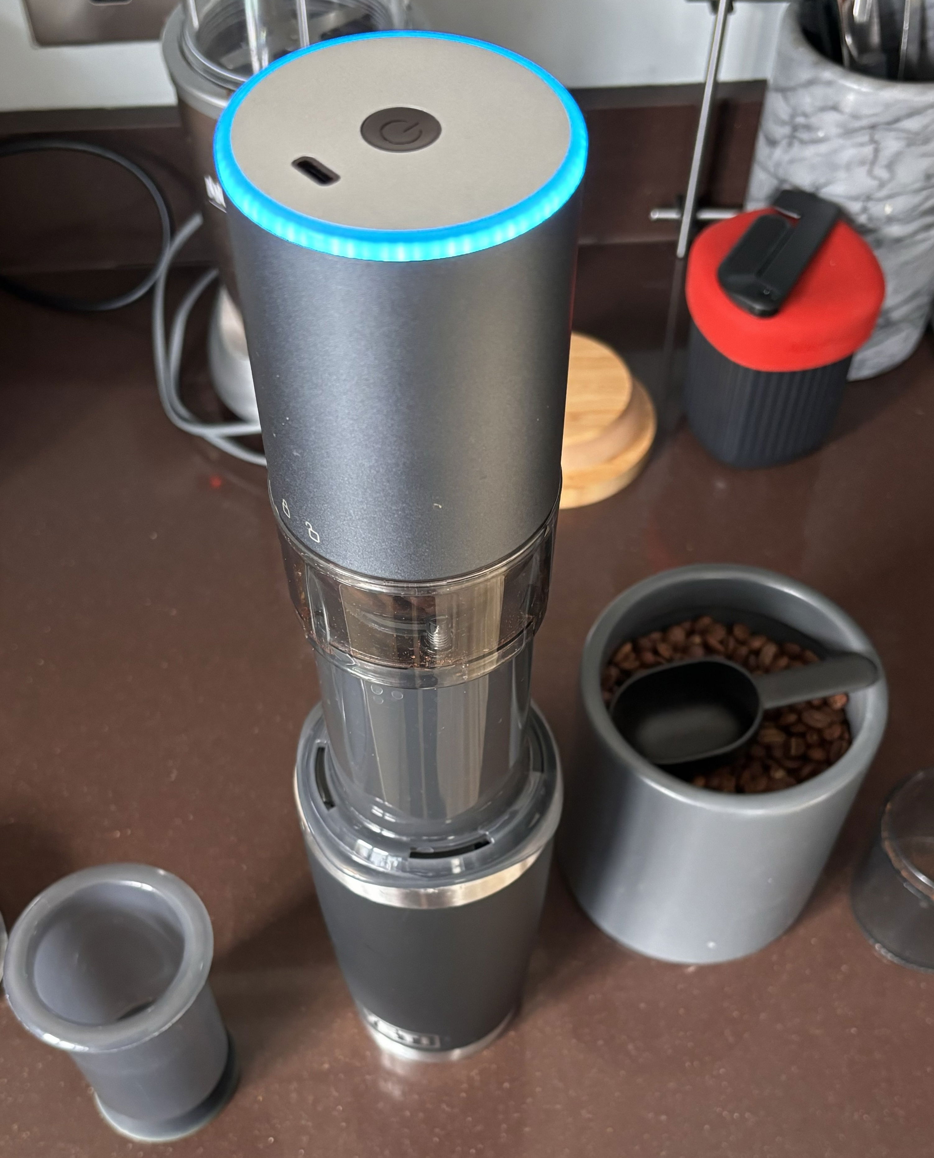 Step two. Showing a coffee cup, AeroPress now topped with an electric burr grinder. It&#39;s grinding the whole beans because there&#39;s a blue ring shinning on top. 